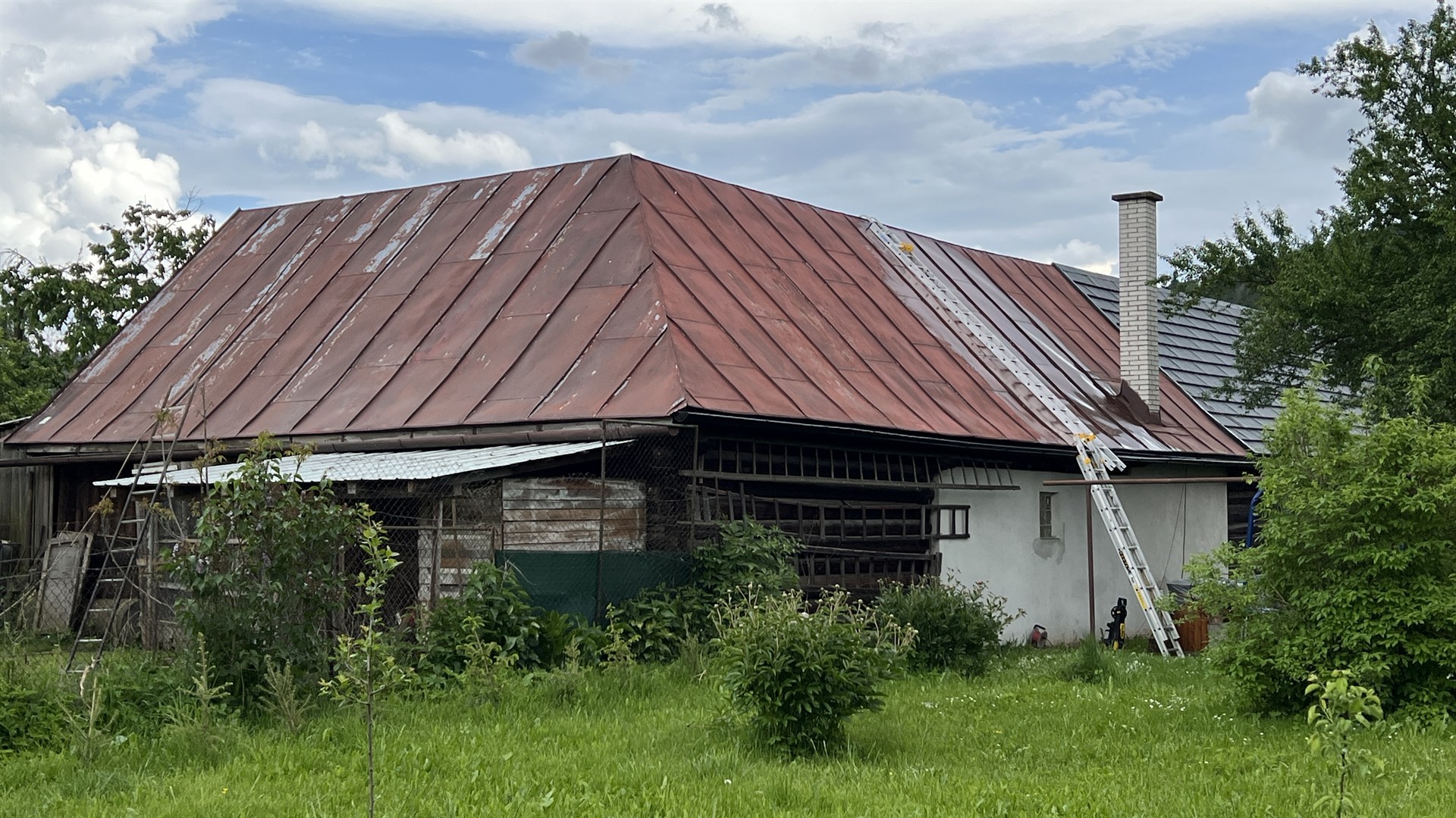 Zadná strana plechovej strechy v Závadke nad Hronom pred renováciou — starý náter, hrdza, oxidácia